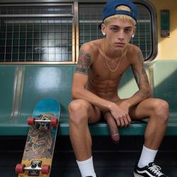 front facing view full body shot, A slim tattooed tough East LA urban skater boy twink with an attitude. Natural laid-back relaxed posture sitting against a seat on a vintage subway {ref1}, masculine with a rugged jaw, a lean slender body, warm golden tanned skin, a smooth hairless body, blond hair, a short buzzcut, hazel eyes, wearing a casual urban streetwear fit, masculine top. slender lean toned build. 18 years old, uncircumcised dick, upper arm tattoos. wearing a blue baseball cap, diamond earrings studs, gold necklace, white socks and VANS skater shoes, he sits mostly naked shirtless, no trousers, with a skateboard resting beside him leaning against the seat. His limp uncircumcised dick is above average, of thick girth, flaccid with pronounced veins and short trimmed curly pubes, his prodigious dick is a thing of beauty, the tip of his uncircumcised dick protrudes out of his tight foreskin, his saggy testicles can be barely be seen tucked behind his dick resting on the edge of the seat.